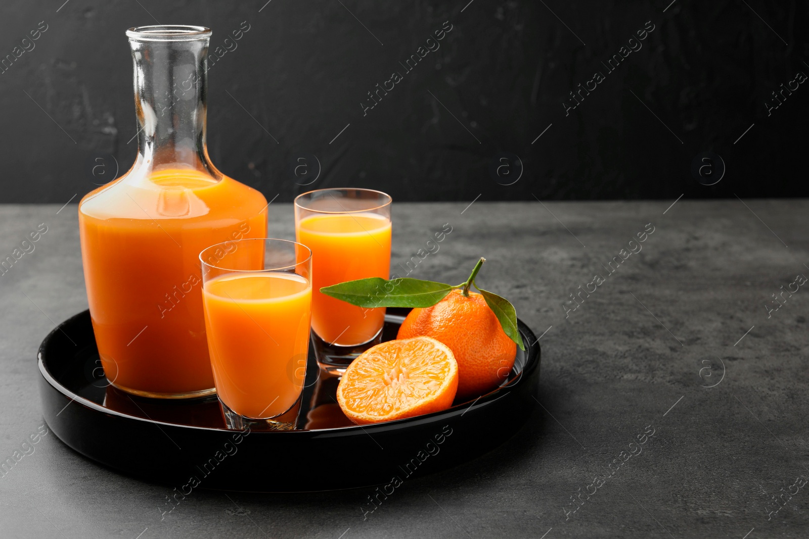 Photo of Delicious tangerine liqueur and fresh fruits on grey table, space for text