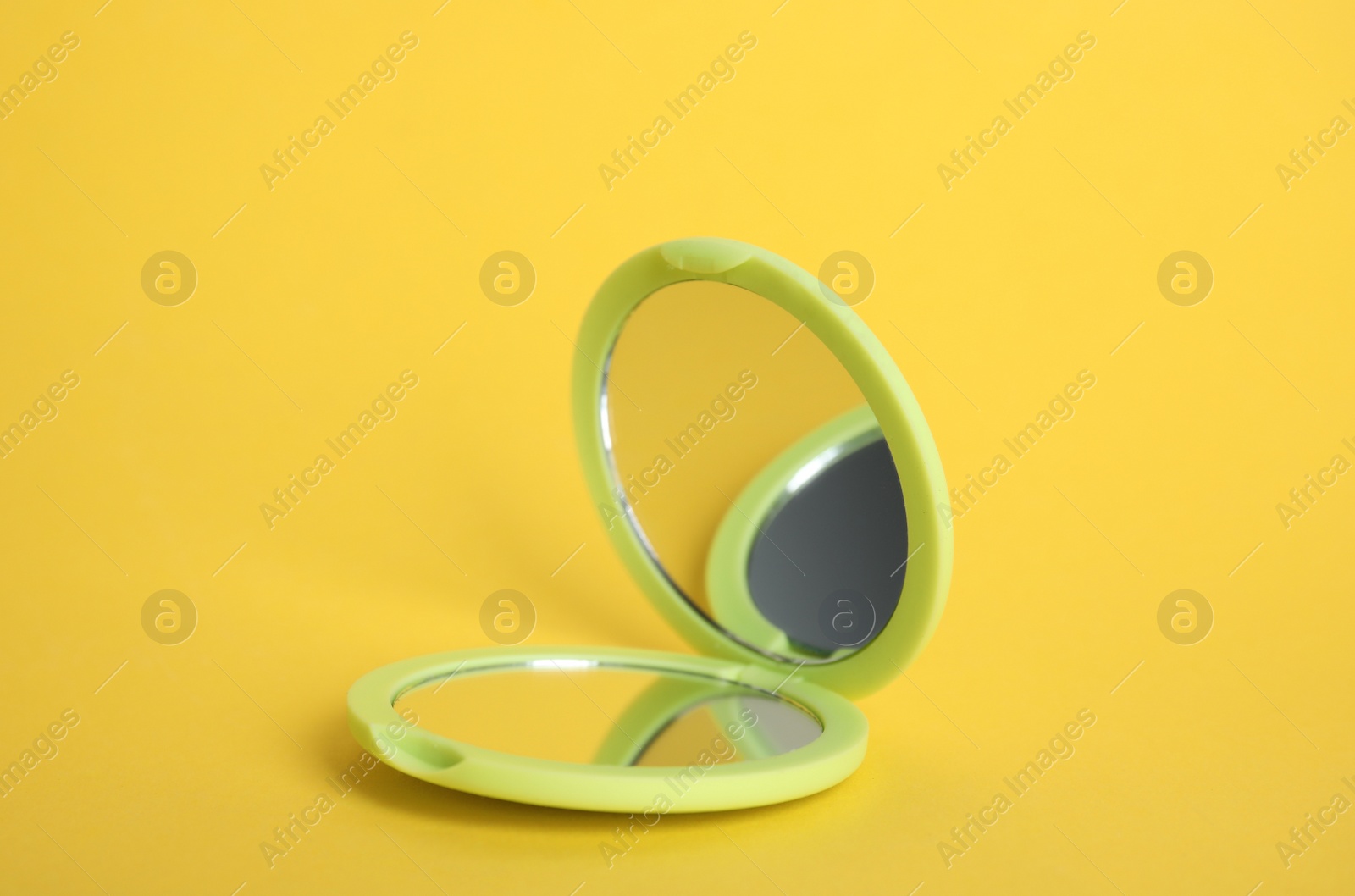 Photo of Stylish cosmetic pocket mirror on yellow background