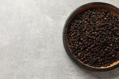 Aromatic spice. Black pepper in bowl on light grey table, top view. Space for text