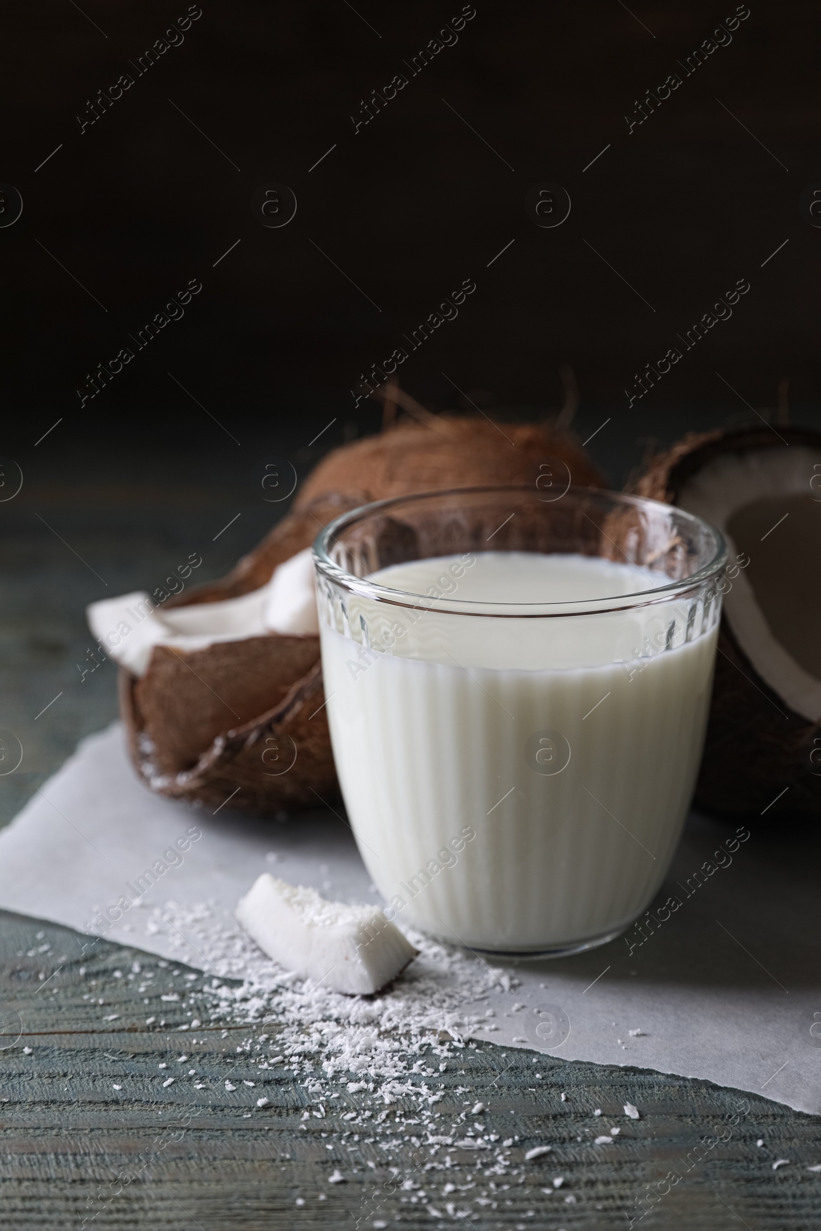 Photo of Glass of delicious coconut milk, flakes and nuts on wooden table