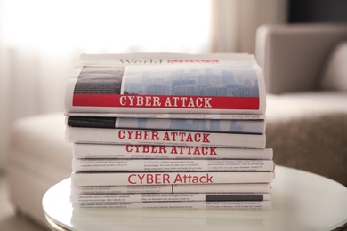 Photo of Stack of newspapers with headlines CYBER ATTACK on table indoors, closeup