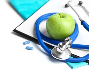 Stethoscope, clipboard and apple on light background. Medical equipment