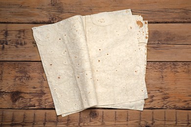 Delicious folded Armenian lavash on wooden table, top view