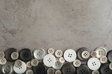 Many plastic sewing buttons on grey background, flat lay. Space for text