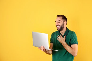 Photo of Man using laptop for video chat on color background. Space for text