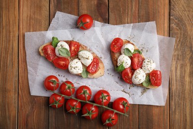 Photo of Delicious sandwiches with mozzarella, fresh tomatoes and basil on wooden table, flat lay
