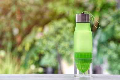 Photo of Sports water bottle on table against blurred background. Space for text