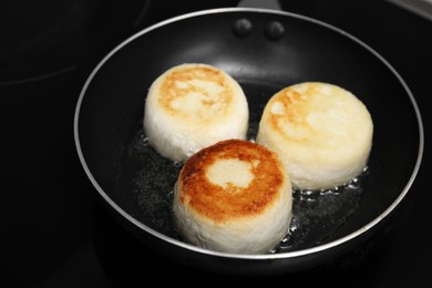 Delicious cottage cheese pancakes in frying pan on cooktop