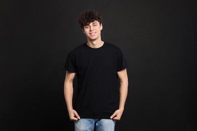 Man wearing stylish t-shirt on black background. Mockup for design