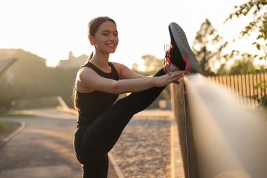 Photo of Attractive happy woman stretching outdoors on sunny day