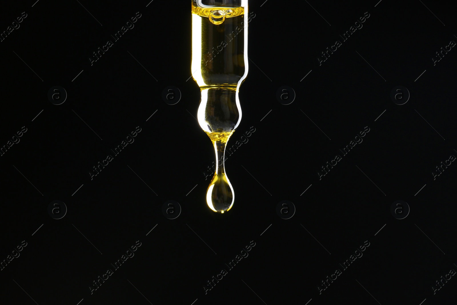 Photo of Dripping tincture from pipette on black background, closeup