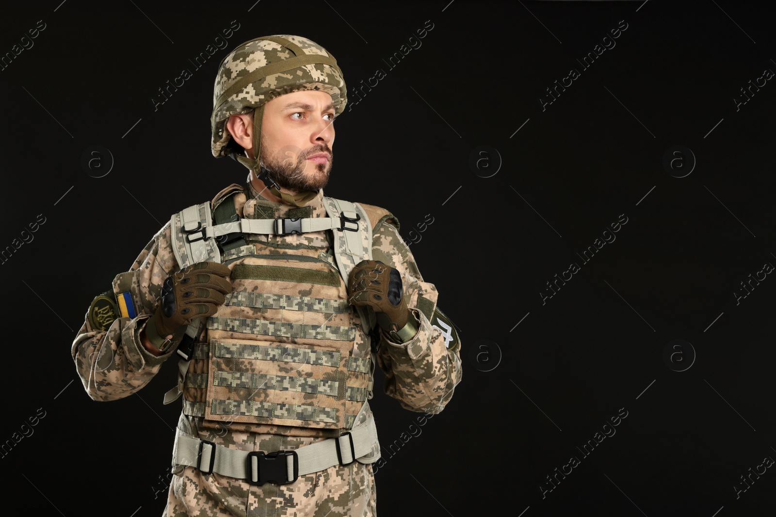 Photo of Soldier in Ukrainian military uniform on black background. Space for text