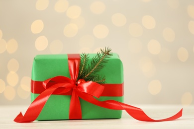 Photo of Christmas gift on wooden table against blurred lights