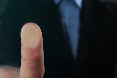 Photo of Businessman pressing control glass of biometric fingerprint scanner, closeup. Space for text