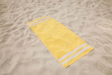 Soft yellow beach towel on sunlit sand