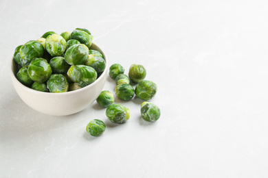 Photo of Frozen Brussels sprouts on light grey marble table, space for text. Vegetable preservation