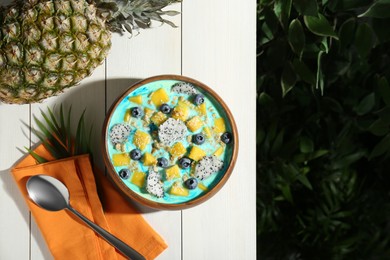 Delicious smoothie bowl with fresh fruits, blueberries and oatmeal served on white wooden table outdoors, flat lay. Space for text