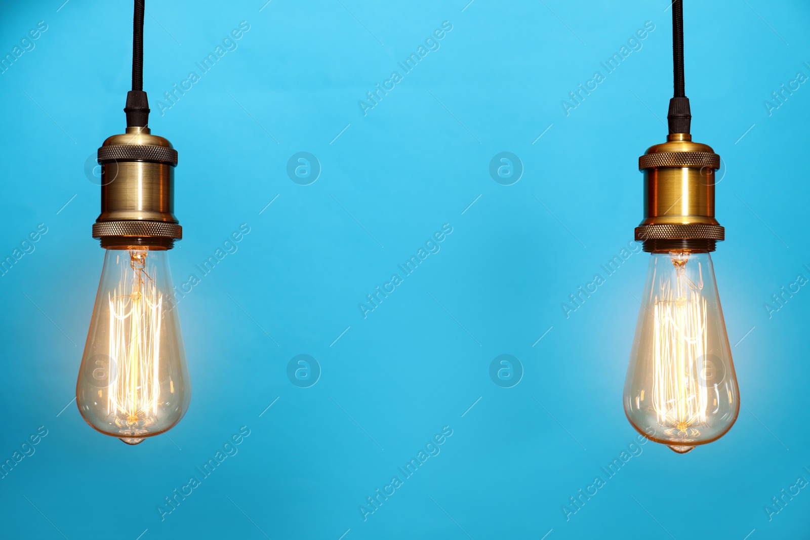 Photo of Pendant lamps with light bulbs on color background, space for text