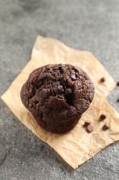 Photo of Delicious chocolate muffin on grey textured table, closeup