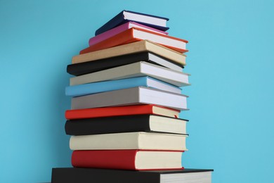 Stack of different books on light blue background
