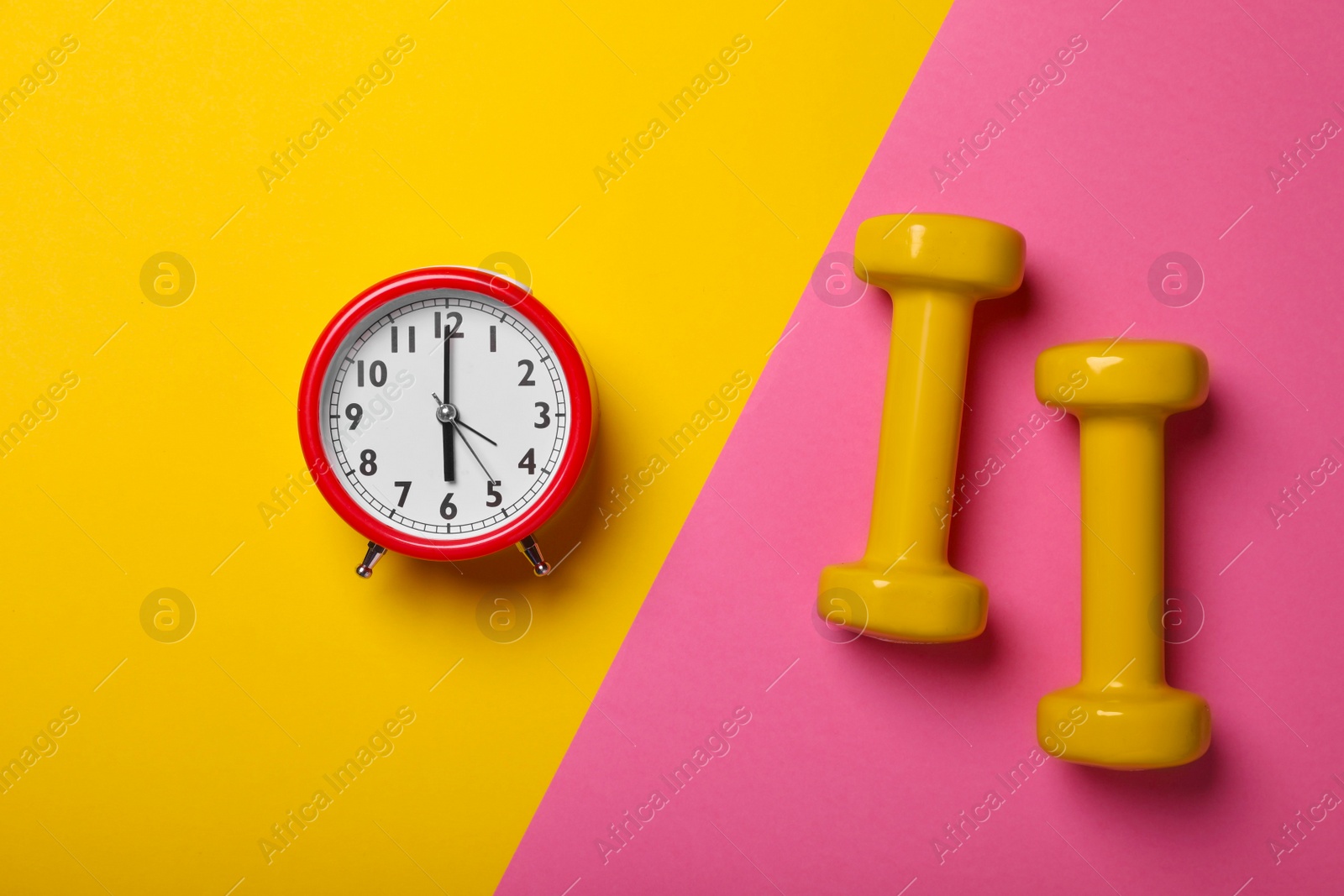 Photo of Alarm clock and dumbbells on color background, flat lay. Morning exercise