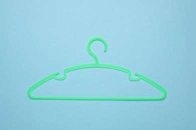 Empty clothes hanger on light blue background, top view