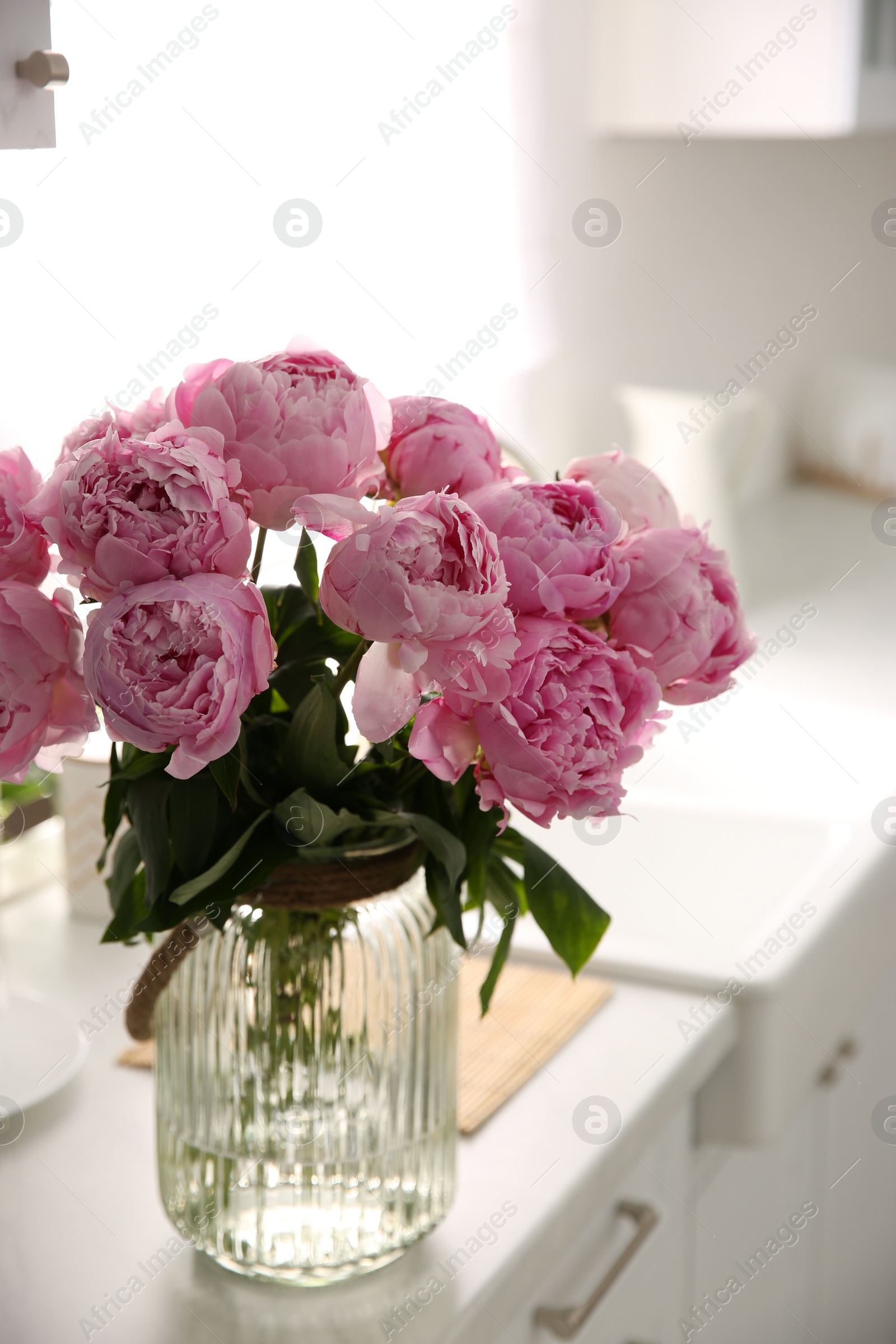 Photo of Vase with bouquet of beautiful pink peonies in kitchen