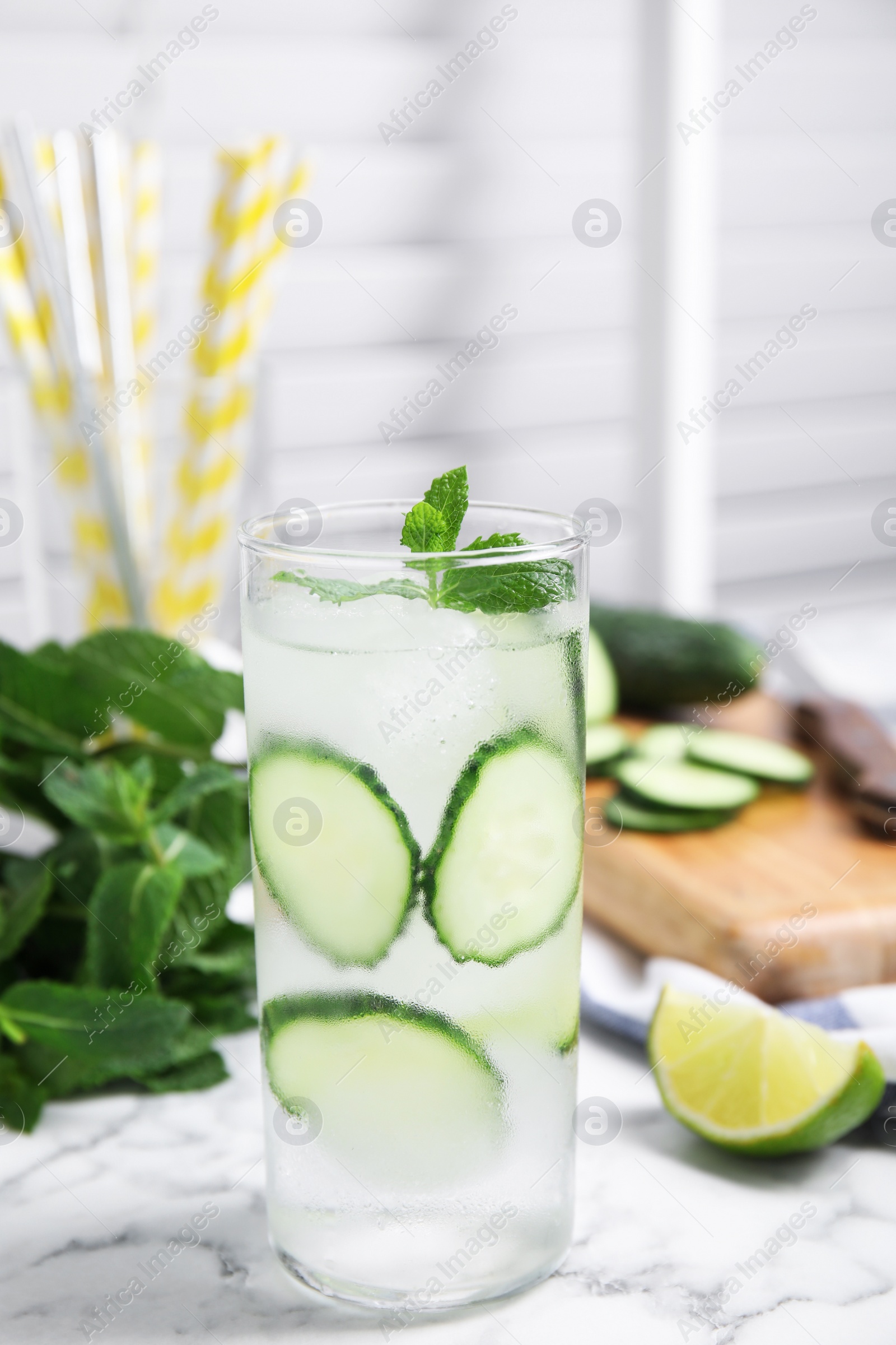 Photo of Glass of refreshing cucumber water with mint on white marble table