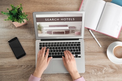 Image of Woman searching hotel using laptop at table, top view. Booking online service