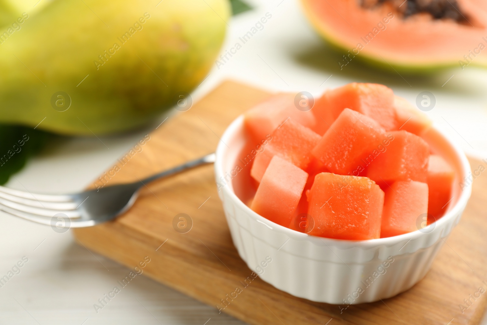 Photo of Fresh diced papaya in bowl on white table, closeup