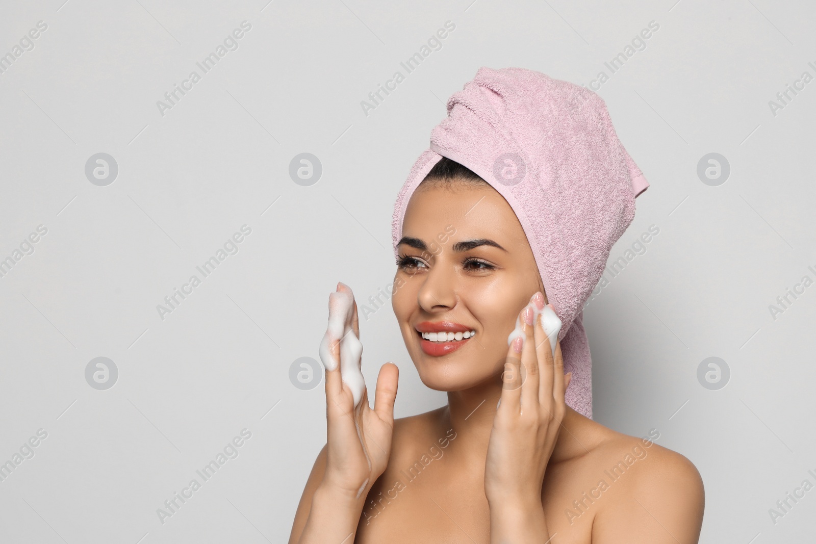 Photo of Beautiful woman applying facial cleansing foam on white background, space for text