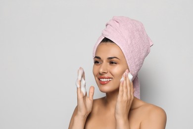 Photo of Beautiful woman applying facial cleansing foam on white background, space for text