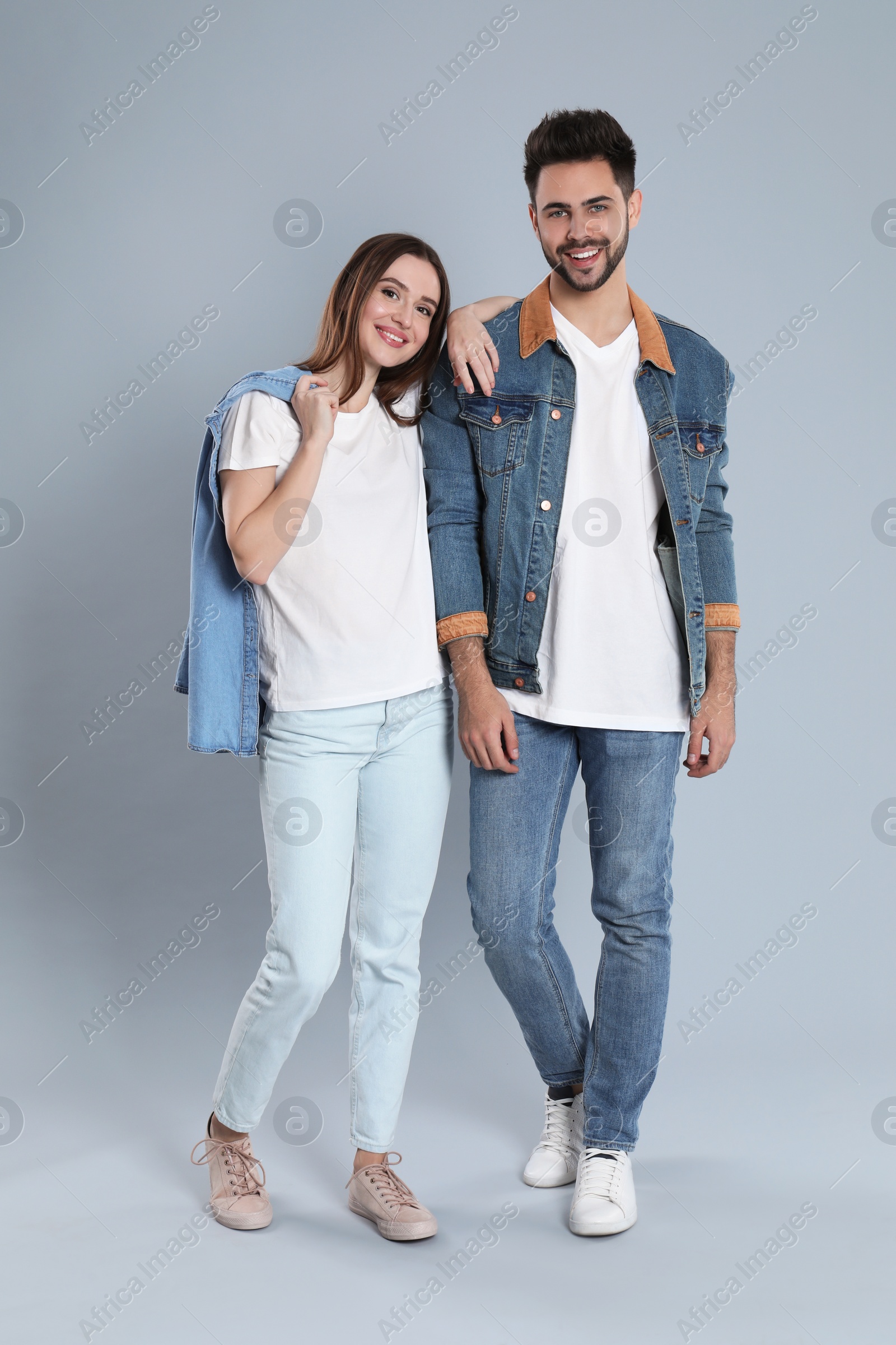 Photo of Young couple in stylish jeans on grey background