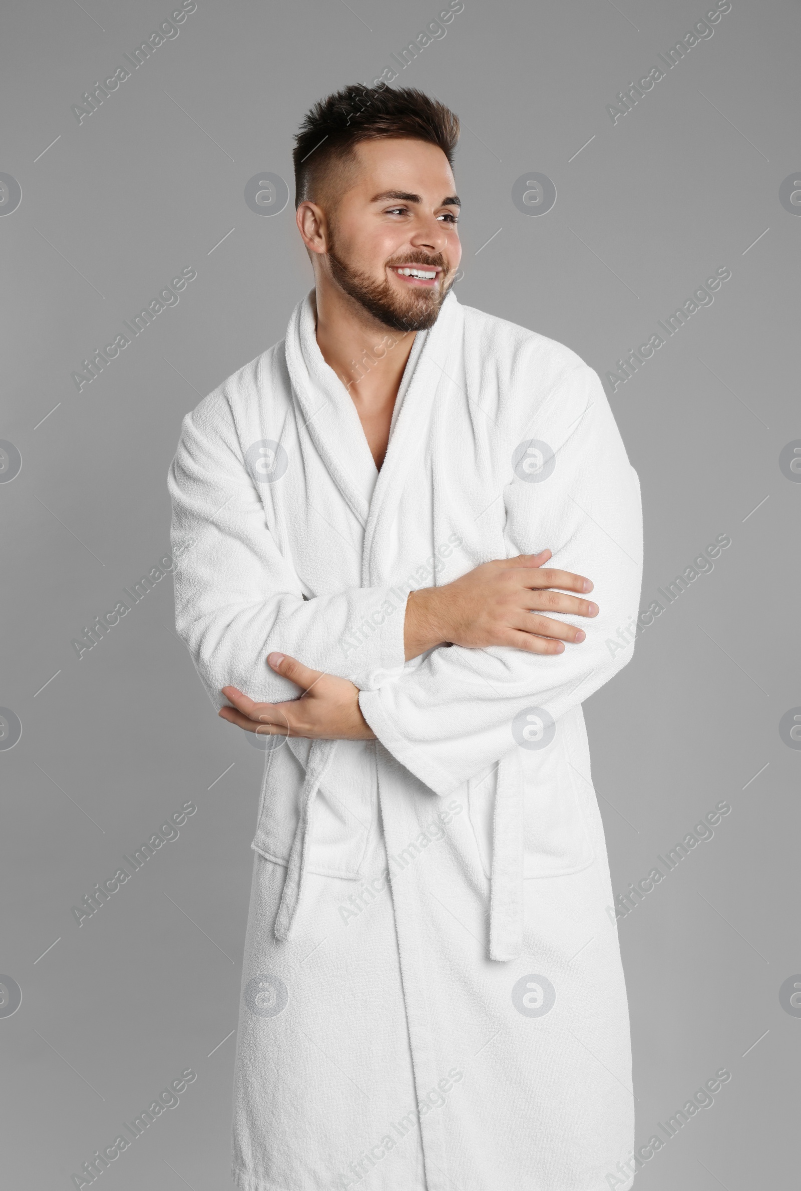 Photo of Happy young man in bathrobe on grey background