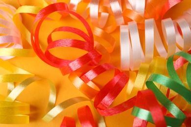 Colorful serpentine streamers on yellow background, closeup