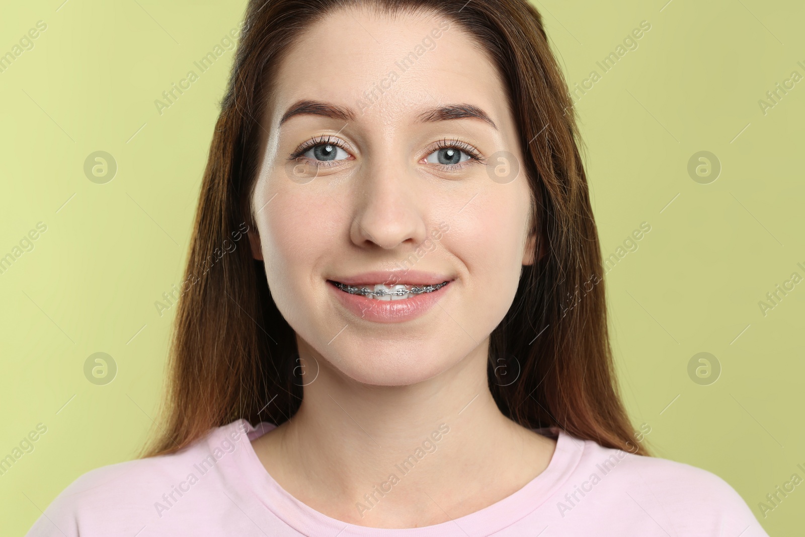 Photo of Portrait of smiling woman with dental braces on light green background