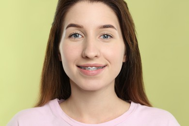 Portrait of smiling woman with dental braces on light green background