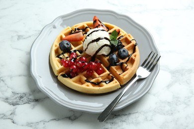 Photo of Delicious Belgian waffles with ice cream, berries and chocolate sauce on light marble table