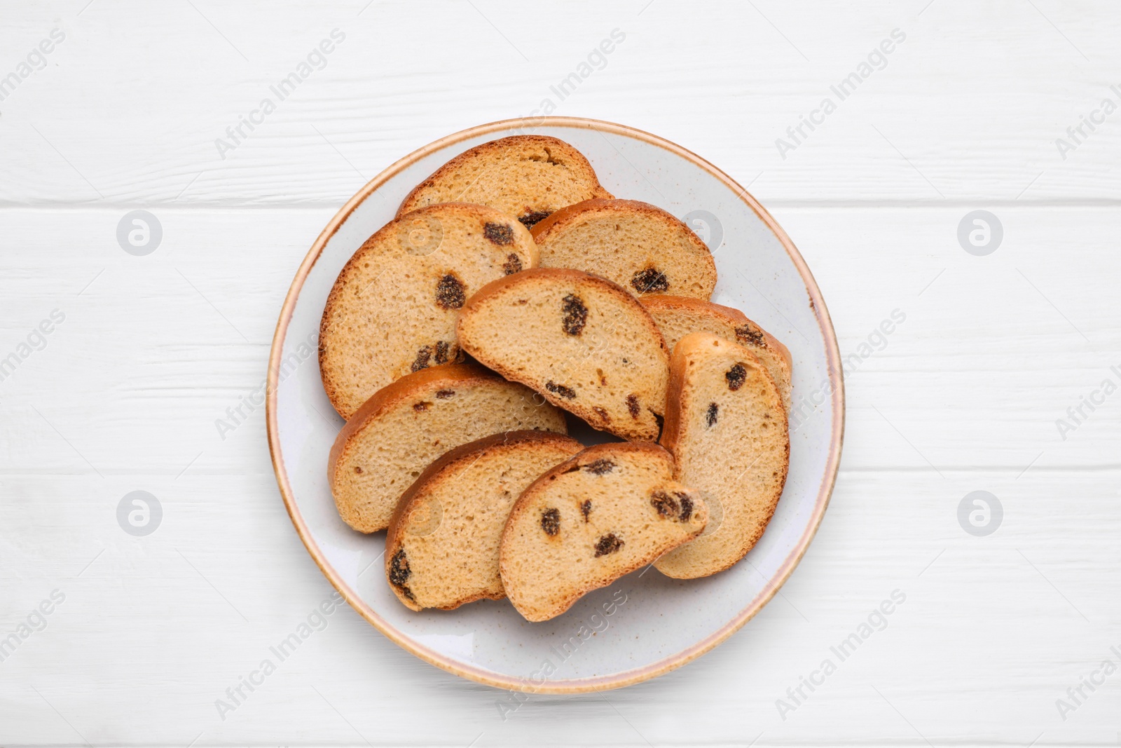 Photo of Plate of sweet hard chuck crackers with raisins on white wooden table, top view