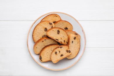 Photo of Plate of sweet hard chuck crackers with raisins on white wooden table, top view