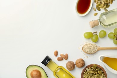 Photo of Vegetable fats. Different oils in glass bottles and ingredients on white table, flat lay. Space for text