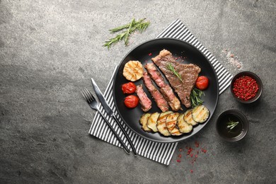 Delicious grilled beef steak with vegetables served on gray table, flat lay. Space for text