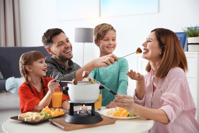 Photo of Happy family enjoying fondue dinner at home