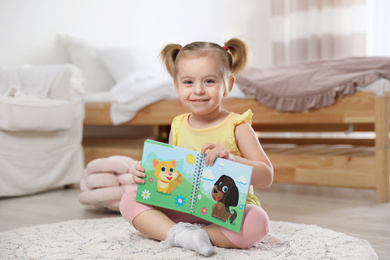 Photo of Cute little girl with book at home