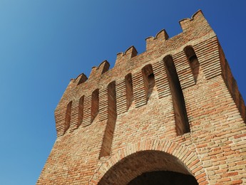 Photo of Brick city tower against blue sky on sunny day, low angle view