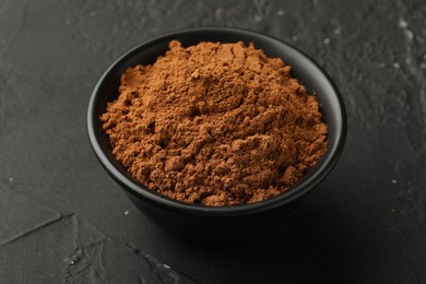 Photo of Aromatic cinnamon powder on black table, closeup