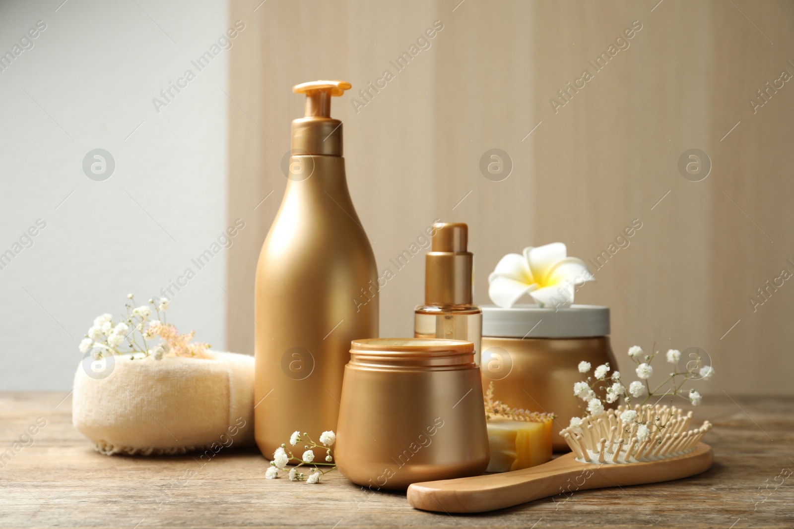 Photo of Set of hair cosmetic products, tools and flowers on wooden table