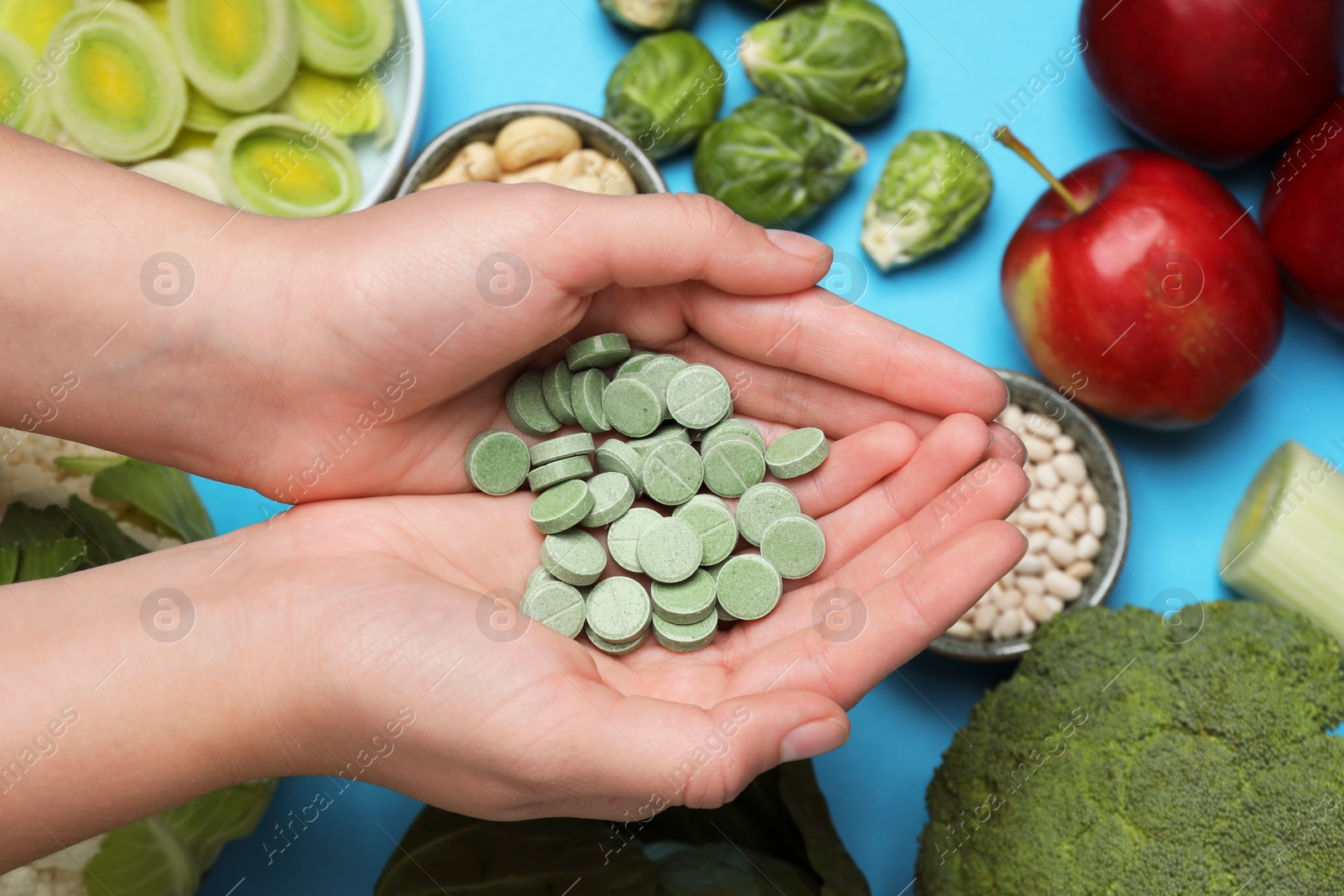 Photo of Woman holding prebiotic pills over food, closeup