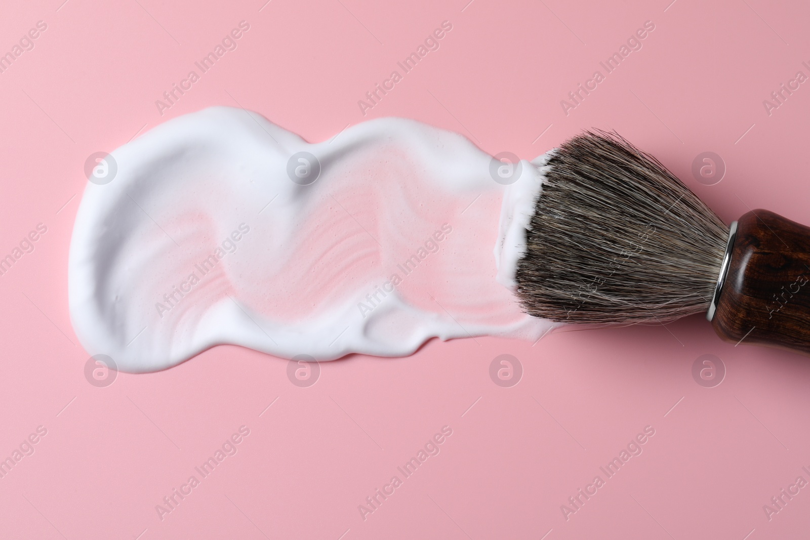 Photo of Brush with shaving foam on pink background, top view