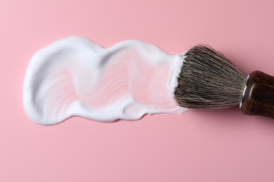 Brush with shaving foam on pink background, top view